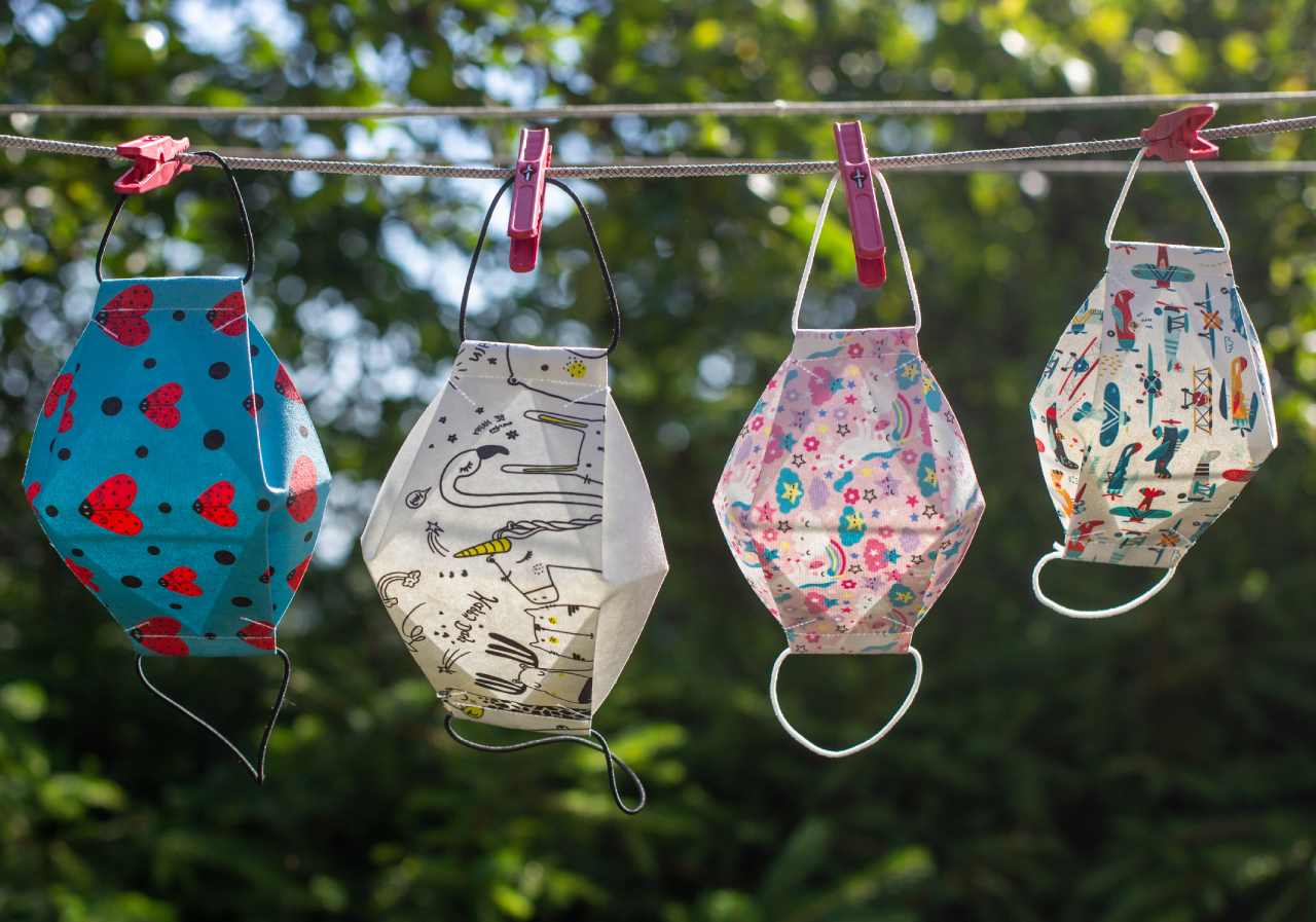 Bunte Stoffmasken hängen auf der Wäscheleine im Garten.