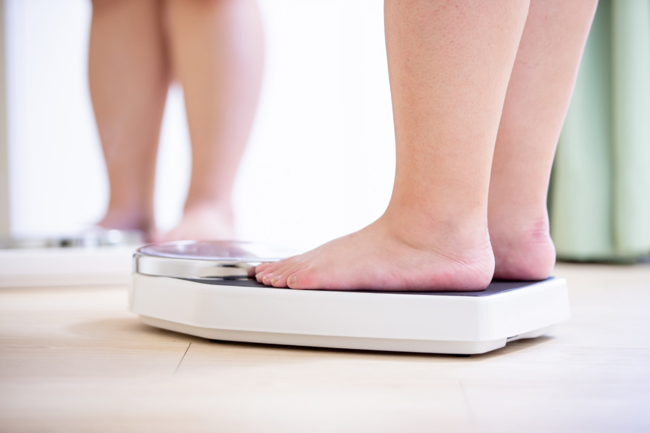 Adipositas und Übergewicht, Füße einer Frau auf der Waage, Hilfe beim Abnehmen.