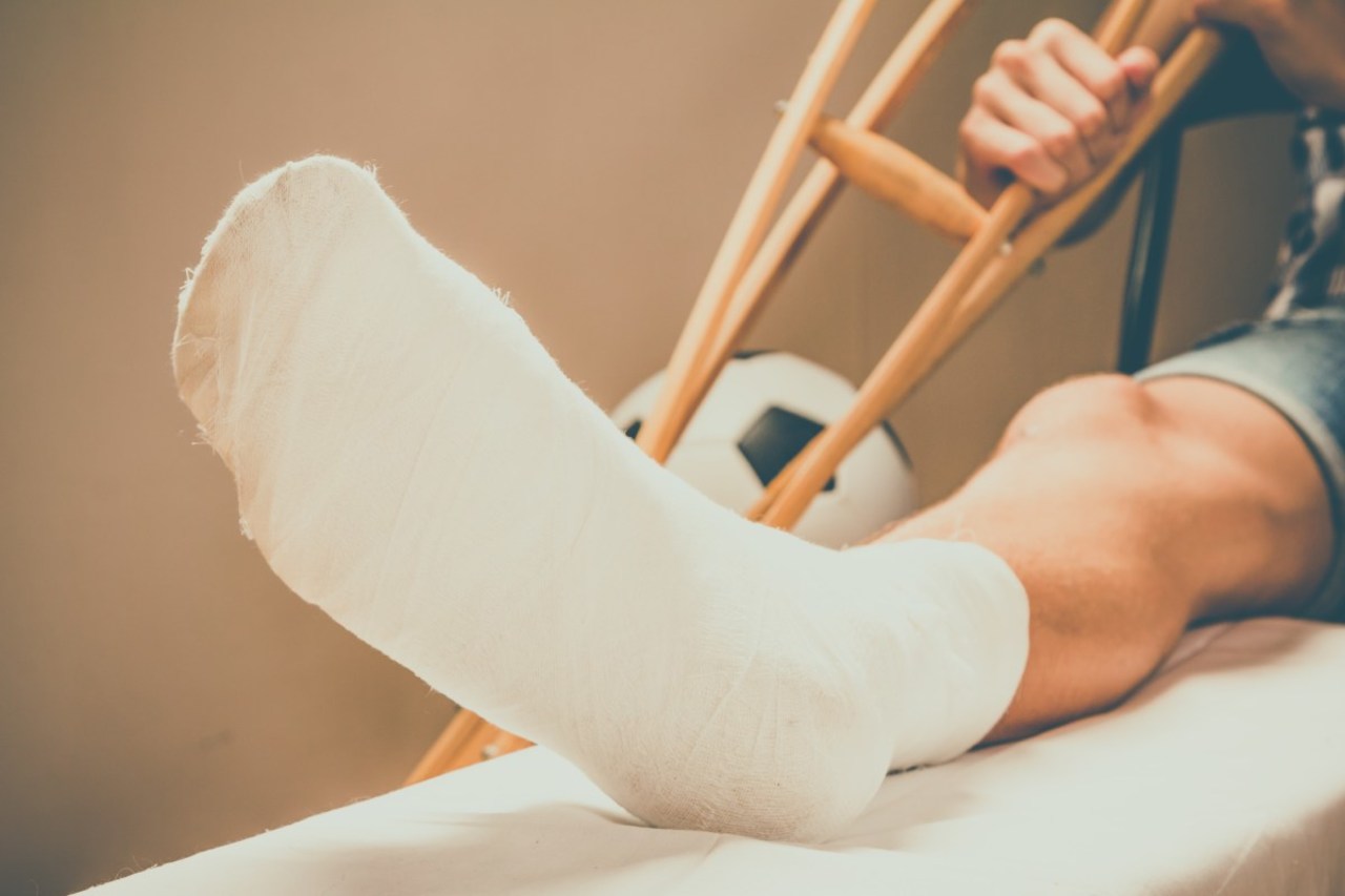Verletzter Fußballspieler mit Verband am Fuss und Krücken.