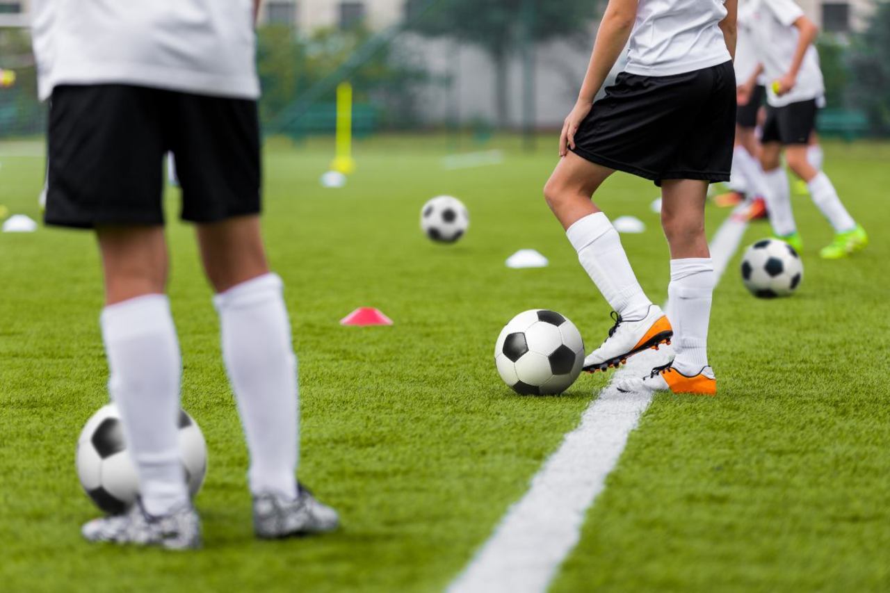 Fußballspieler warten beim Training mit Bällen an der Linie.