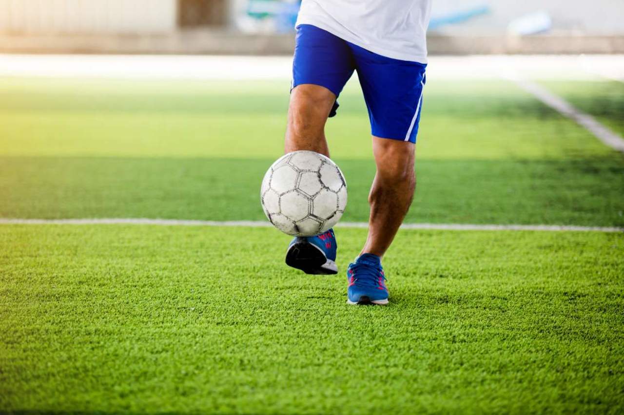 Fußballer haben oft O-Beine. Spieler balanciert Ball auf seinem Fuß.