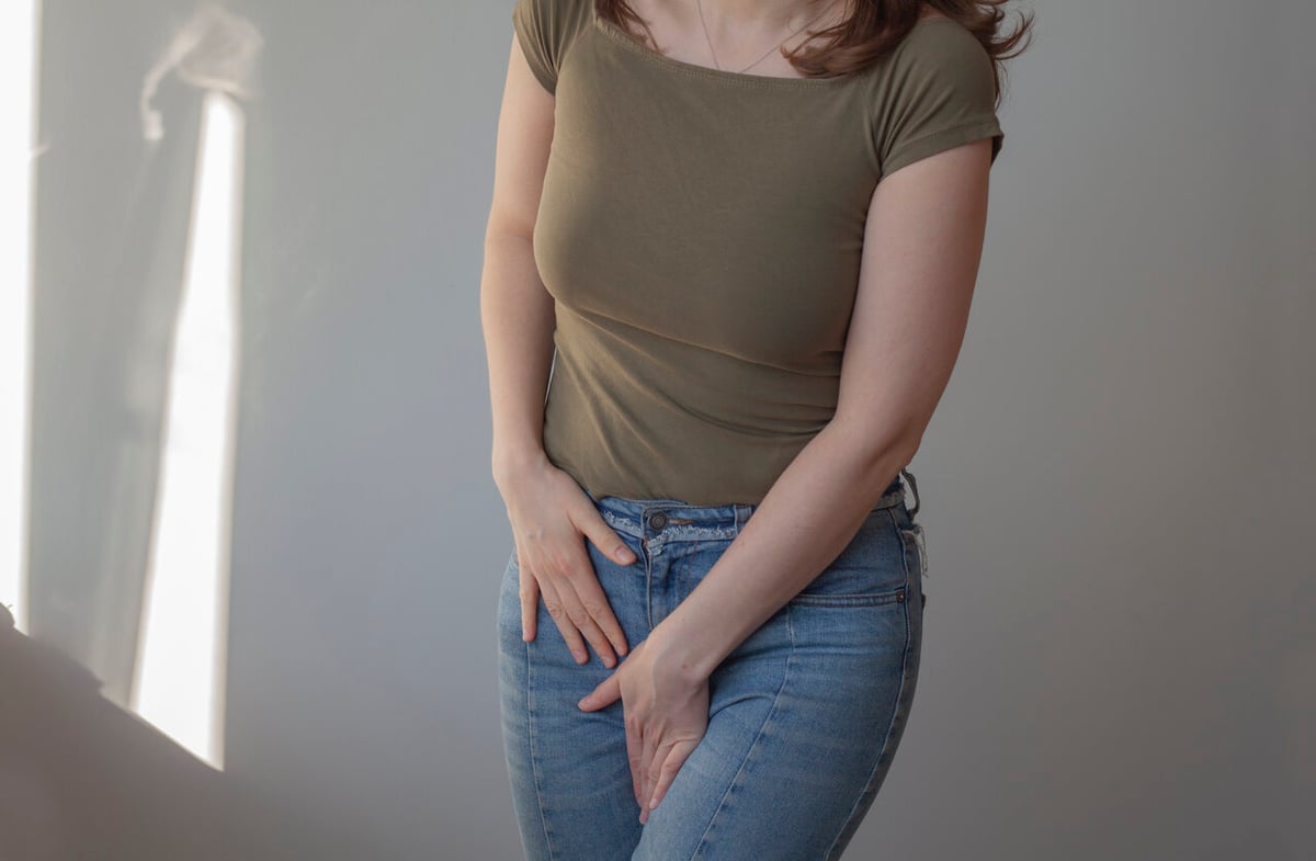 Frau hält eine Hand in ihren Intimbereich.
