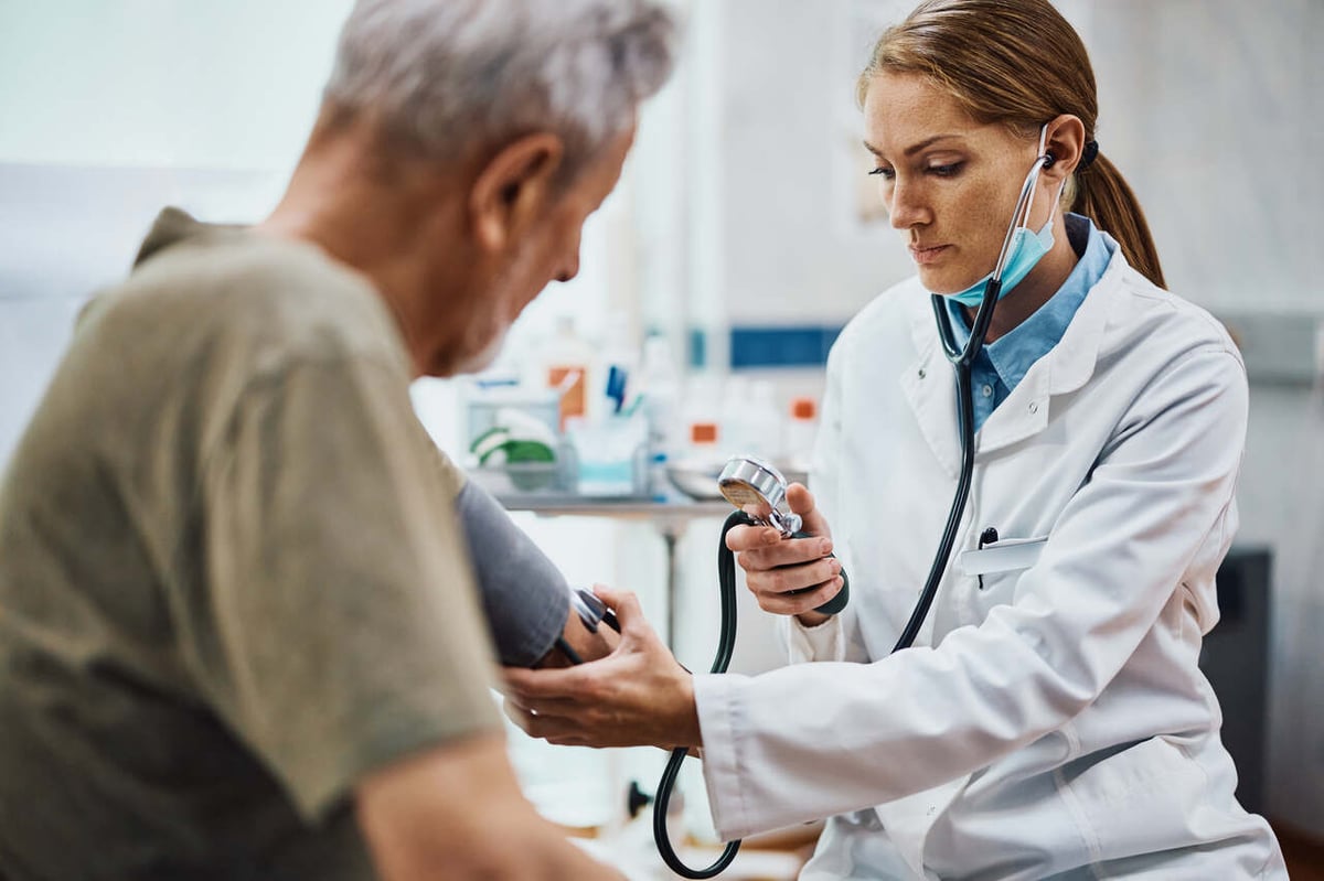Junge Ärztin misst bei ihrem Patienten den Blutdruck.