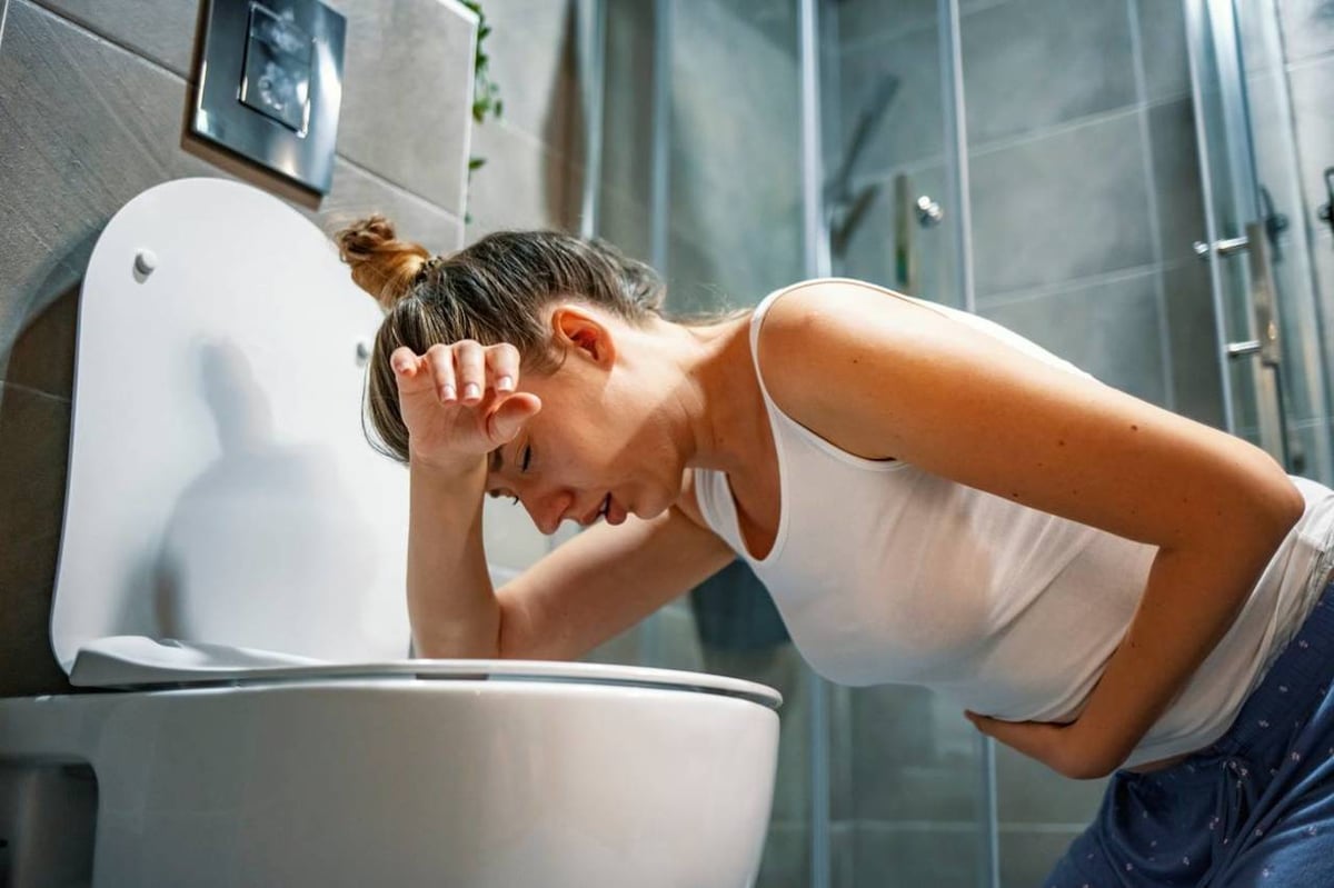 Frau erbricht sich auf der Toilette.