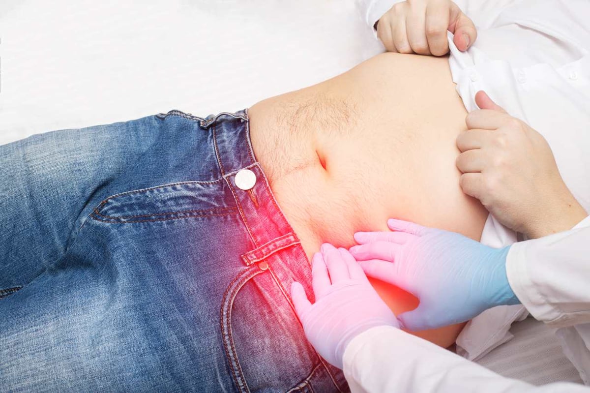 Arzt untersucht Patient durch Palpation des linken Unterbauchs 