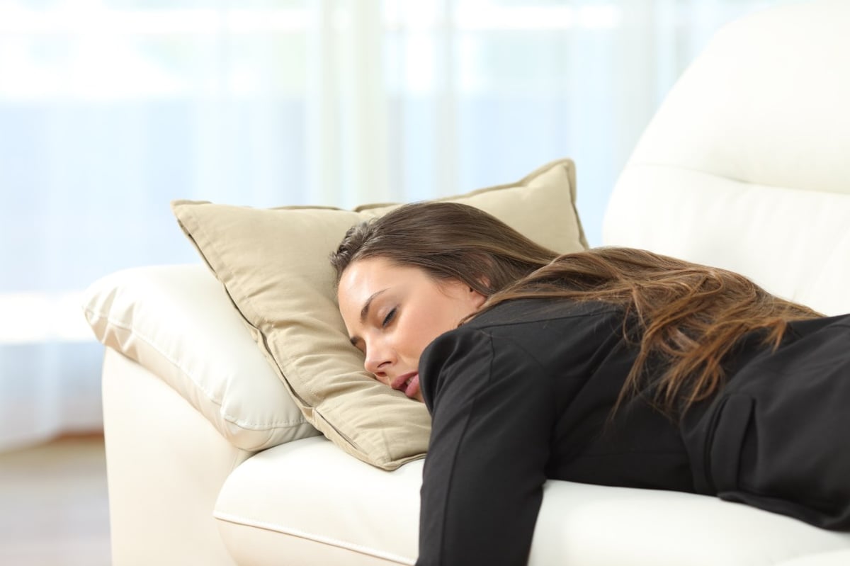 Eine junge Frau ist sehr müde und schläft auf dem Sofa.