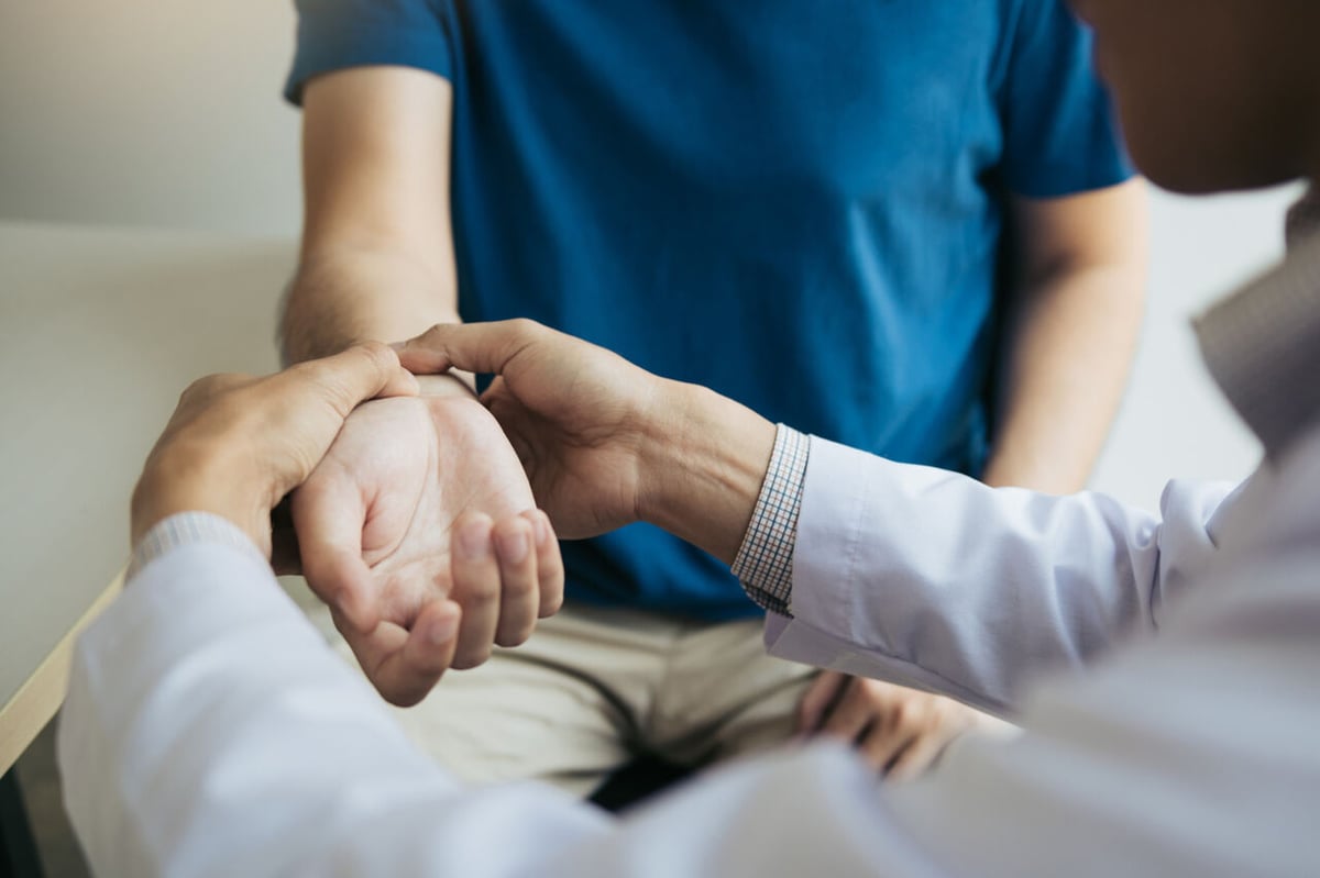 Arzt untersucht Handgelenk von Patientin.
