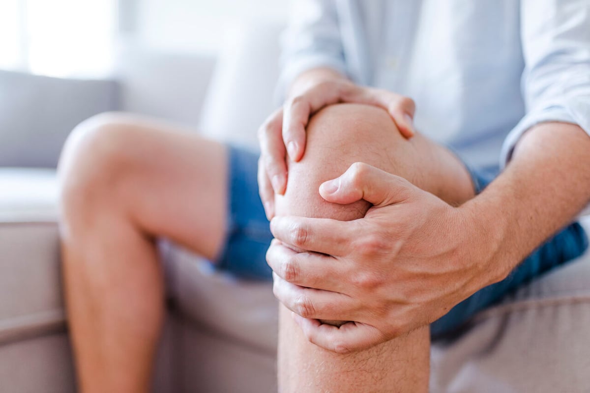 Ein Mann hält sich vor Schmerzen das Knie.