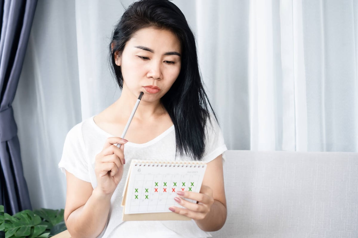 Frau betrachtet mit Stift am Mund ihren Kalender.
