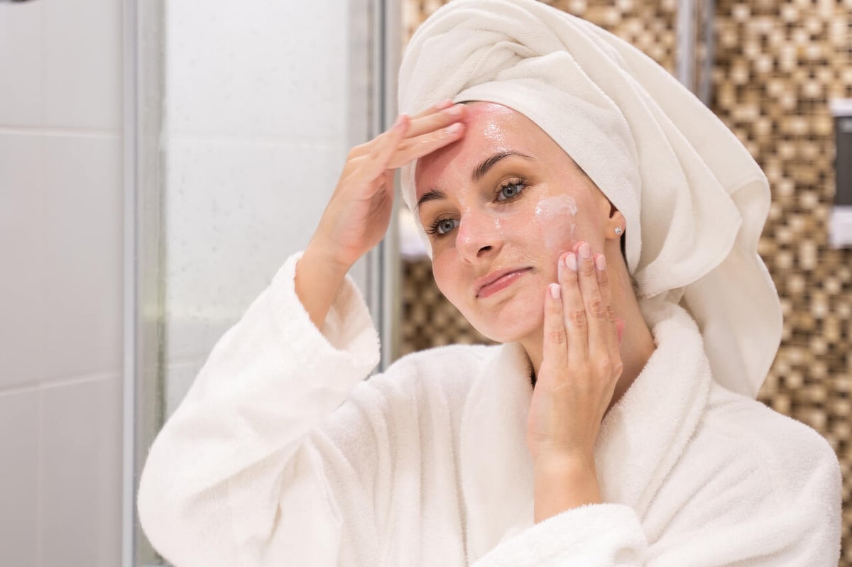 Frau im Badezimmer behandelt ihr Gesicht mit Gel.