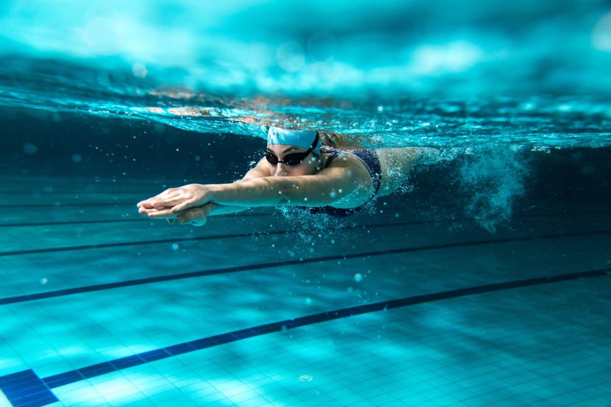 Junge Frau schwimmt im Schwimmbad und taucht gerade ins Wasser ein.