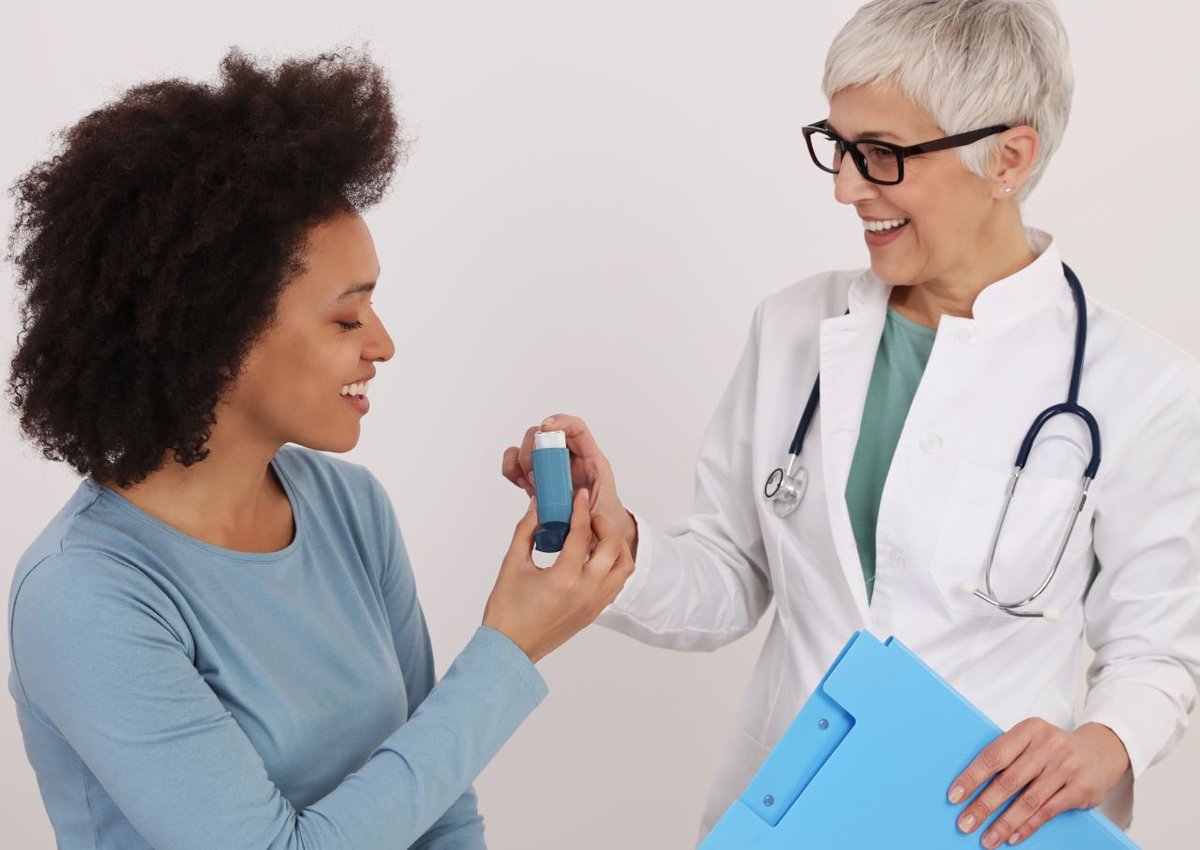 Eine Ärztin reicht einer Patientin mit Asthma einen Inhalator.