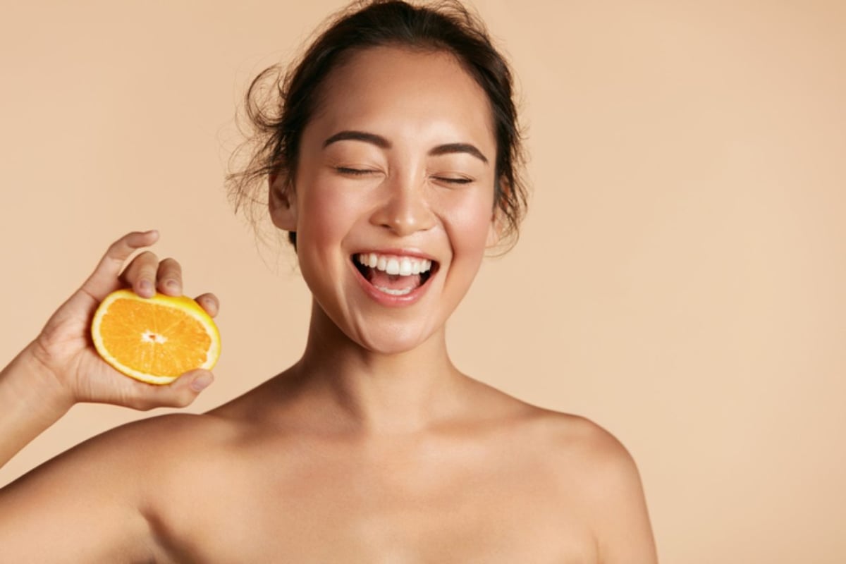 Junge Frau mit schöner Haut hält Orange.