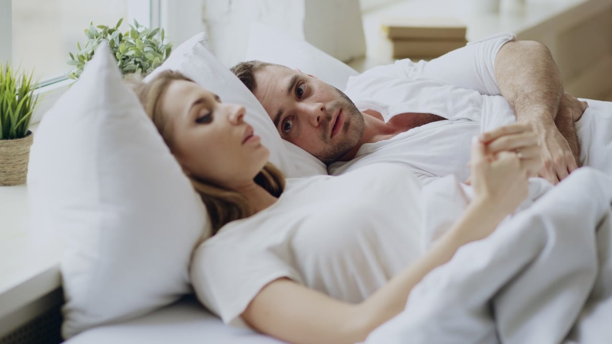 Ein Paar liegt im Bett und führt ein Gespräch.