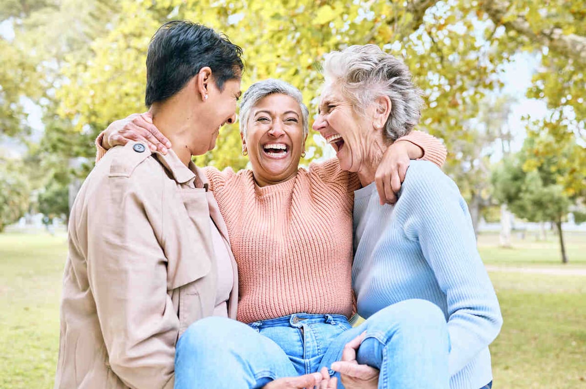 Drei ältere Frauen lachen im Park.