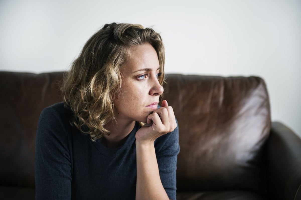 Frau mit innerer Unruhe nachdenklich auf Sofa.