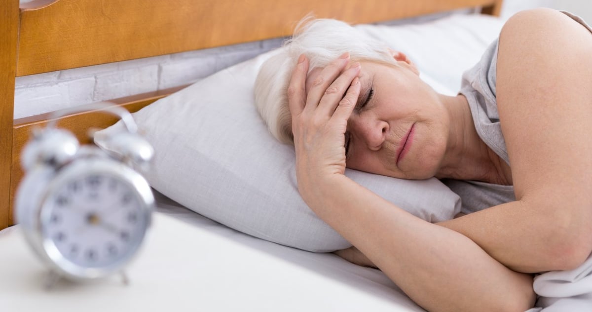 Frau liegt mit Migräne im Bett.