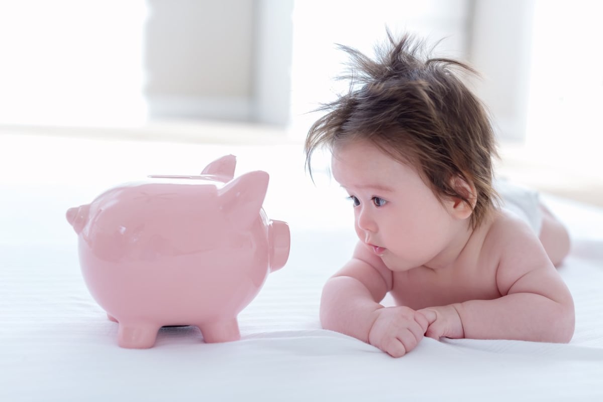 Es ist ein Baby mit einem Sparschwein zu sehen.