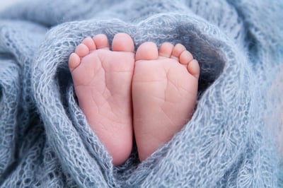 Kleine Zehen, Babyfüße, eingewickelt in eine Herzdecke.