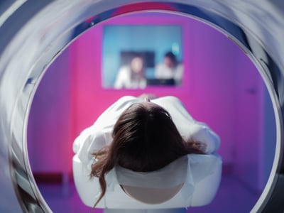 Eine Patientin liegt auf dem Gerätetisch und wird in den Tomographen eingefahren.