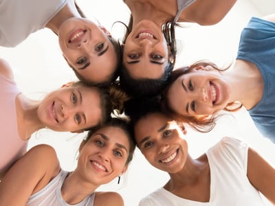 Gruppe von jungen Frauen steht im Kreis und guckt nach unten.
