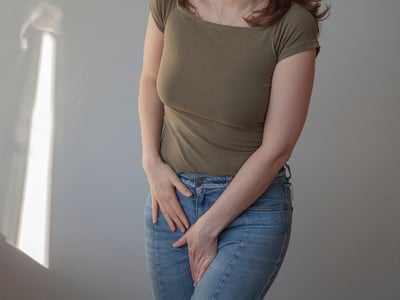 Frau hält eine Hand in ihren Intimbereich.