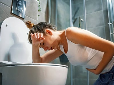 Frau erbricht sich auf der Toilette.