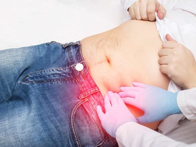 Arzt untersucht Patient durch Palpation des linken Unterbauchs 