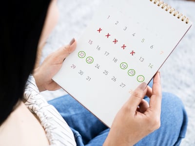 Frau betrachtet Zykluskalender in ihrer Hand.