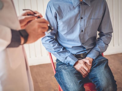 Junger Mann mit Beschwerden im Genitalbereich spricht mit Arzt 