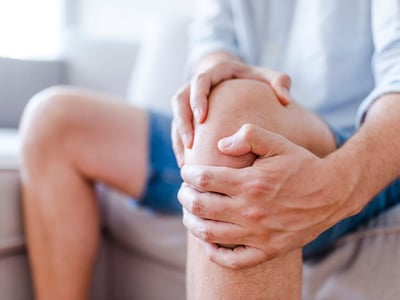 Ein Mann hält sich vor Schmerzen das Knie.