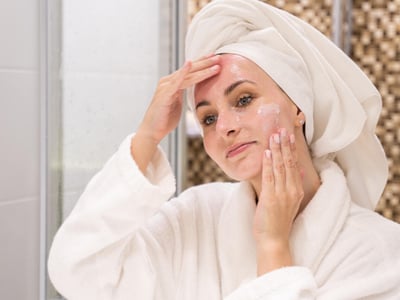 Frau im Badezimmer behandelt ihr Gesicht mit Gel.
