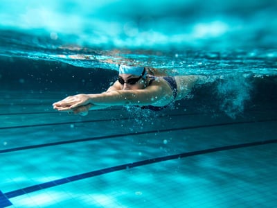 Junge Frau schwimmt im Schwimmbad und taucht gerade ins Wasser ein.