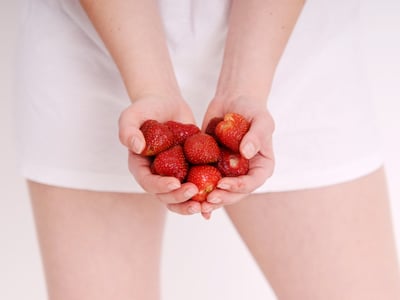 Frau hält Erdbeeren in der Hand.