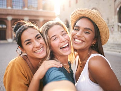 Drei Frauen lachen in die Kamera.