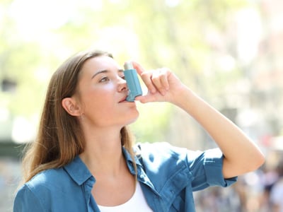 Eine Frau hält einen Asthma-Inhalator.
