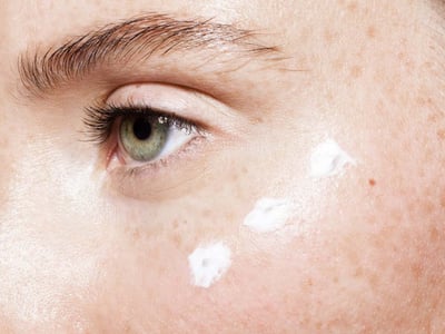 Frau mit drei Tupfen Creme auf der Wange.