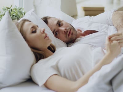 Ein Paar liegt im Bett und führt ein Gespräch.