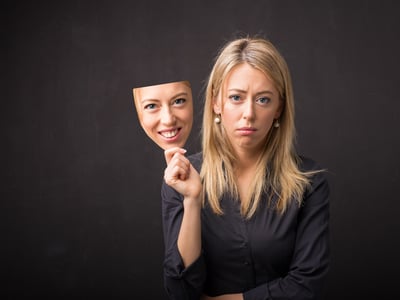 Darstellung von Depression: Traurige Frau hat eine glückliche Maske.