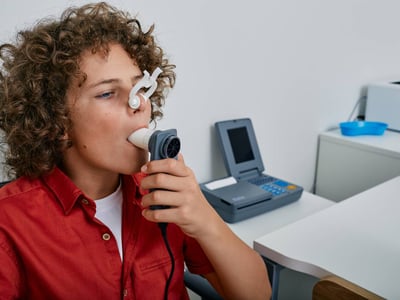 Ein Junge macht in einer Arztpraxis einen Lungenfunktionstest mittels Spirometrie.