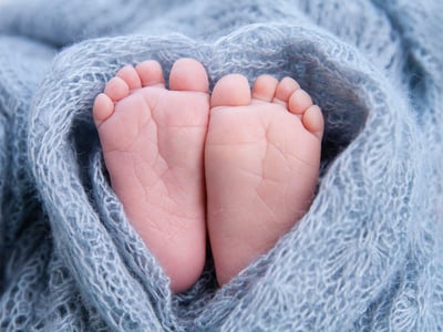Kleine Zehen, Babyfüße, eingewickelt in eine Herzdecke.