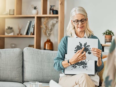 Psychologin sitzt auf Sofa und zeigt einen Rohrschachtest.