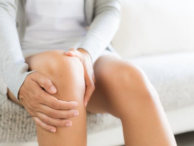Frau massiert ihr schmerzendes Knie.