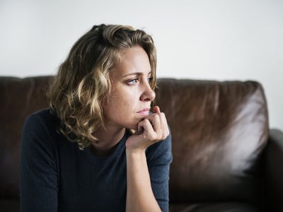 Frau mit innerer Unruhe nachdenklich auf Sofa.