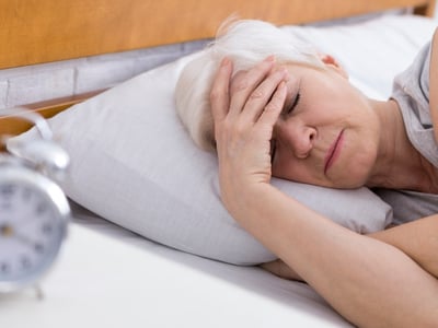 Frau liegt mit Migräne im Bett.