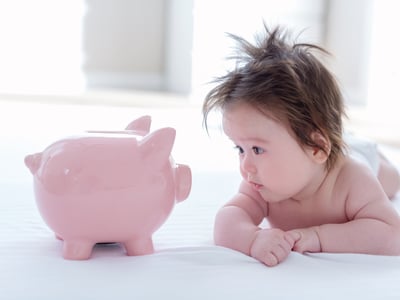 Es ist ein Baby mit einem Sparschwein zu sehen.