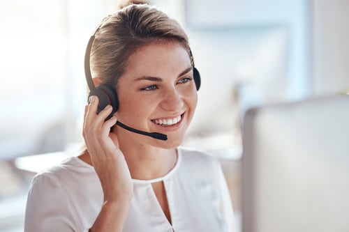 Eine Frau im Kundenservice telefoniert mit Headset am Computer.