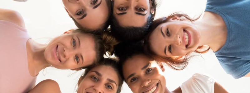 Gruppe von jungen Frauen steht im Kreis und guckt nach unten.