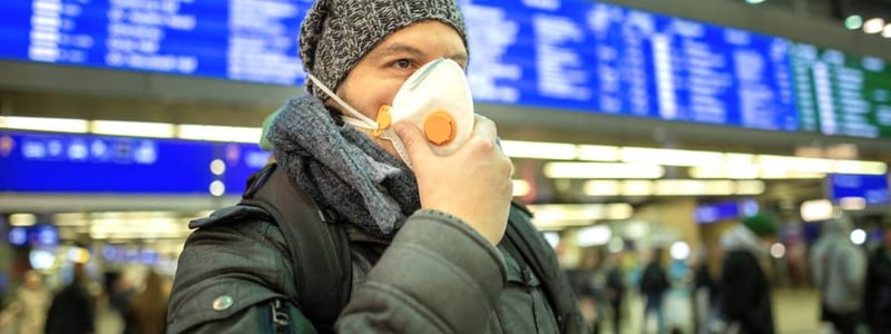 Ein Mann steht zu Beginn der Coronapandemie mit Mundschutz auf einem Bahnhof.
