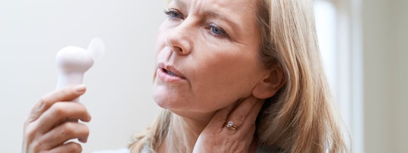 Hormonersatztherapie (HET). Frau mit Hitzewallungen hält Ventilator.